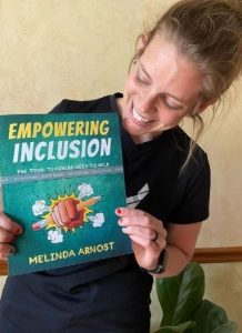 Teacher and author Melinda Arnost smiles as she shows a copy of her book, "Empowering Inclusion".