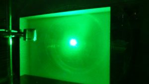 Green laser striking a white board