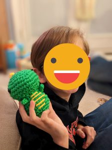 photo of child holding dinosaur amigurumi
