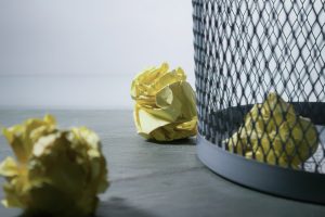 crumpled up student papers in and around a trash can